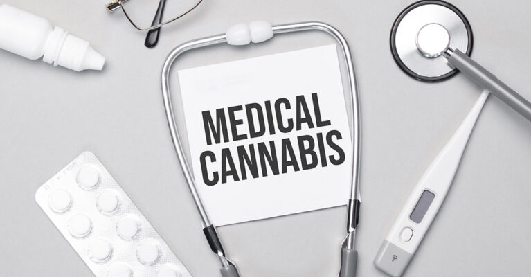 Medical cannabis written on paper in between real stethoscope on a top down view of a table