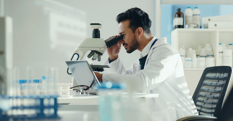 Scientist examining samples under microscope.