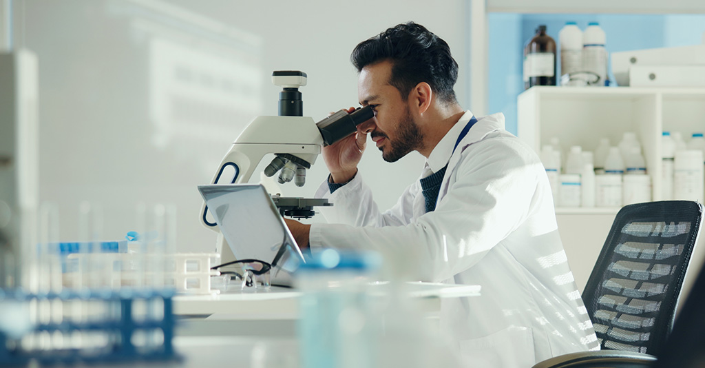 Scientist examining samples under microscope.