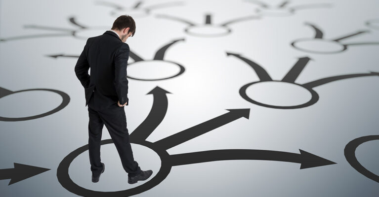 Man standing among directional arrows.