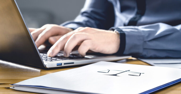 Person typing on laptop with documents