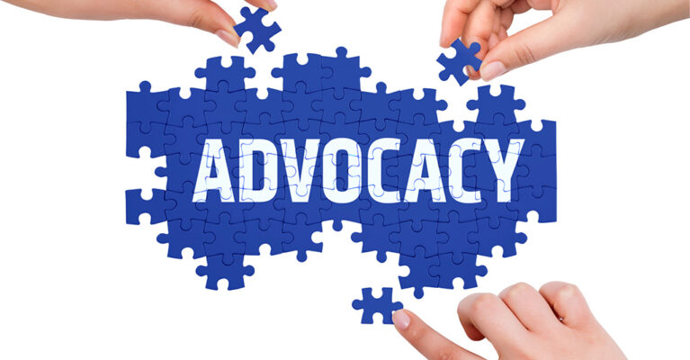 Hands assembling puzzle pieces spelling advocacy